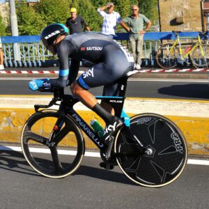 A cyclist in a black and blue Team Sky uniform rides a Pinarello bike during a time trial, with spectators behind a barrier, symbolizing the significance of the number 40 in endurance sports.