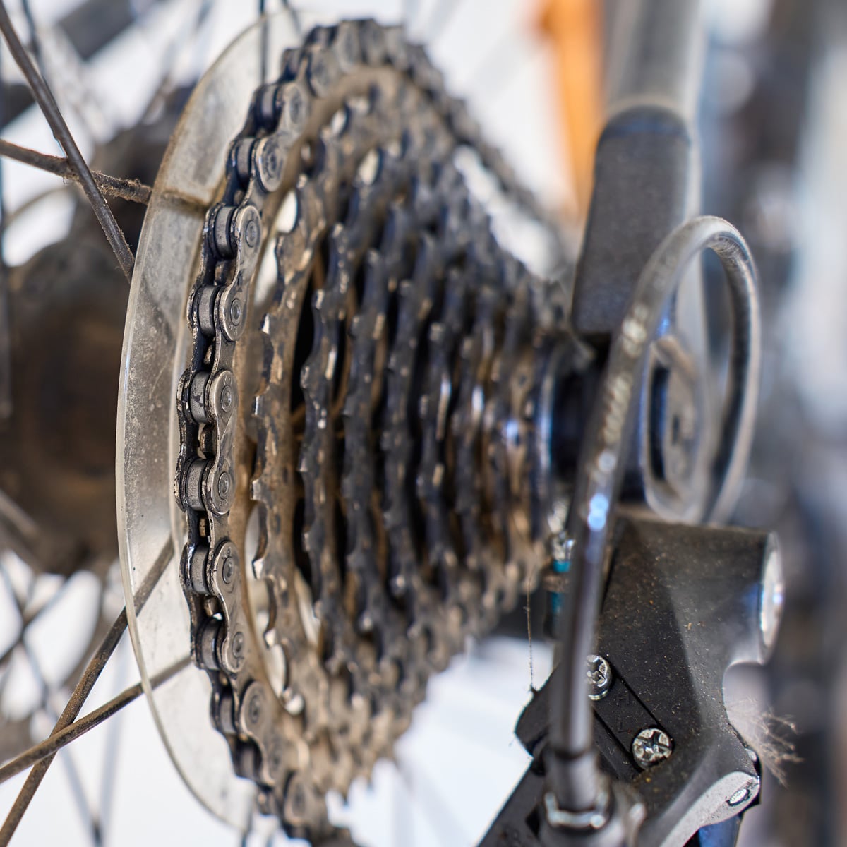 Close-up of a bicycle’s rear gear cassette, chain, and derailleur, showing the metal cogs and bike spokes in detail. The image highlights the mechanical components and intricate parts of the gear system with a focus on the concept of the granny gear.