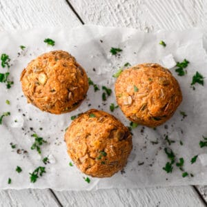 Three baked vegan meat balls sit on parchment paper, garnished with chopped parsley. Enjoy this creation perfect for athletes!